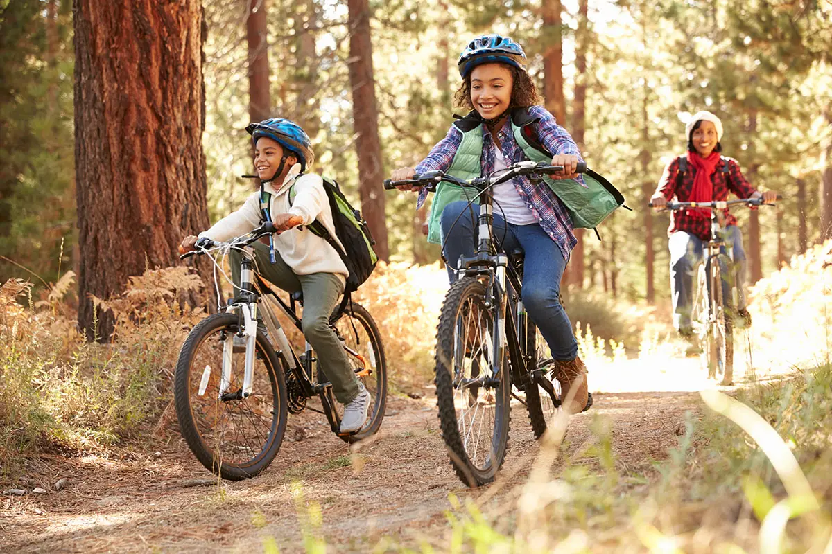 Grandparents With Children Cycling Through Fall Woodland