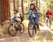 Grandparents With Children Cycling Through Fall Woodland